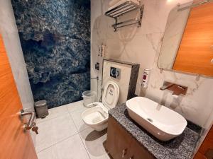 a bathroom with a toilet and a sink at Hotel Rosewood in Prayagraj +3 photos