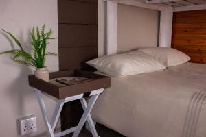 a bed with a night stand with a plant on it at Nama-Qua Game Reserve in Vredendal