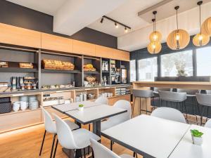 a restaurant with tables and chairs and a counter at B&B HOTEL Saarbrücken-Ost in Saarbrücken