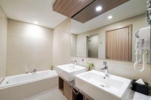 a bathroom with two sinks and a large mirror at Aston Kemayoran City Hotel in Jakarta