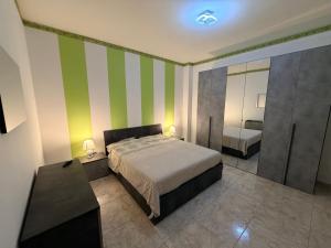 a bedroom with a bed and a green and white striped wall at House raffy in San Severo