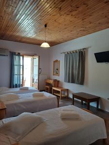 a room with three beds and a tv on the wall at Siroco's Rooms And Studios in Parikia