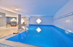 a large swimming pool with blue water in a room at Schöne 3-Zi-Wohnung mit "in-door-pool", "Gym" und "Spielraum" und frisch renoviertem Bad an der Promenade direkt am Scharbeutzer Strand in Scharbeutz