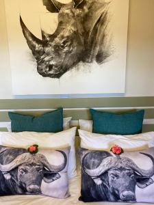 a bed with pillows and a painting of a rhino at Bushveld Venue in Mabula