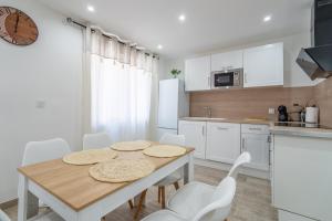 a kitchen with a wooden table and white cabinets at Port-la-Nouvelle 4p in Port-la-Nouvelle