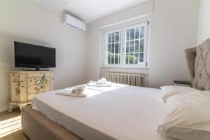 a bedroom with a large white bed and a flat screen tv at Villa Sofia casa con giardino e spiaggia condivisa in Pettenasco
