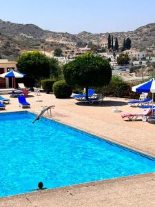 a swimming pool with chairs and umbrellas at The Citrus Valley in Pissouri