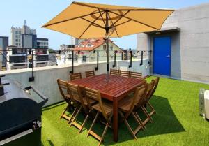 a wooden table with chairs and an umbrella on a roof at Daecheon Mud Gongju Pension in Boryeong