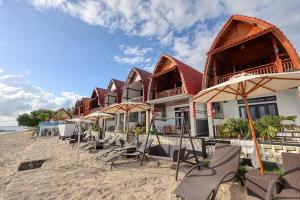 a row of houses on the beach with chairs and umbrellas at Road Beach Cottages in Nusa Penida