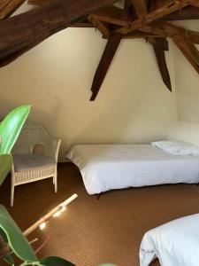 a bedroom with two beds and a chair in a attic at Maison Périgourdine familiale in Saint-Jean-dʼEyraud
