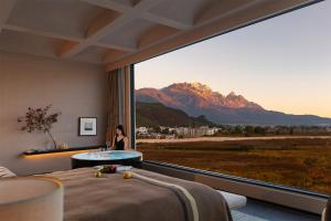 a woman sitting in a room with a large window at Lijiang Chenxi View Hotel in Lijiang
