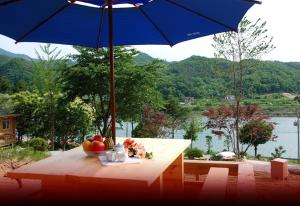 a table with a bowl of fruit and an umbrella at dagagada pension in Hwach'ŏn