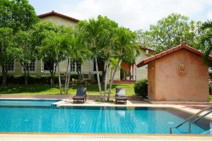 a swimming pool with two chairs and a house at La Villa des Chien in Ban Nong Chap Tao