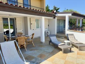 a patio with chairs and a table and a television at Villa Thalea in Diano Marina