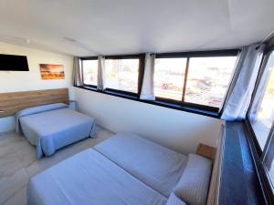 ein Schlafzimmer mit zwei Betten und zwei Fenstern in der Unterkunft Nch Hotel Torremolinos in Torremolinos