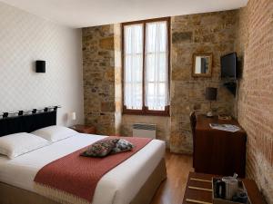 a bedroom with a bed and a brick wall at Hôtellerie de l'Abbaye Saint Amand in Saint-Amand-de-Coly