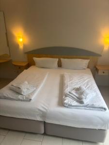 a bed with white sheets and towels on it at Haus Blinkfüer in Wangerooge