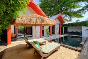 a patio with a umbrella and chairs and a pool at Tolani Resort Koh Samui in Lamai