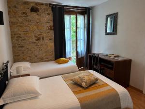 a bedroom with two beds and a desk and a window at Hôtellerie de l'Abbaye Saint Amand in Saint-Amand-de-Coly