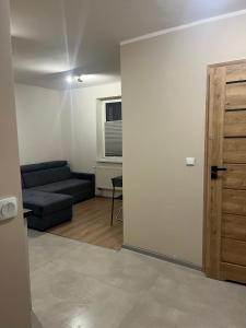 a living room with a couch and a door at Apartament przy kortach 3 in Bytom