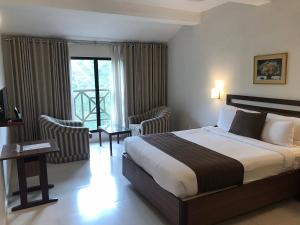 a hotel room with a bed and a balcony at Abad Copper Castle Resort in Munnar +47 photos