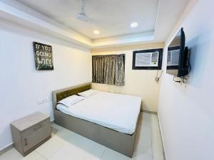 a small bedroom with a bed and a television at Hotel Sunview in Kolkata
