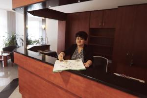 a woman sitting at a desk signing a paper at Land-gut-Hotel Seeblick in Klietz