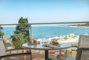 a table on a balcony with a view of the ocean at Marea Suites, Valamar Collection in Poreč