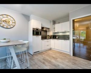 a kitchen with white cabinets and a table and a clock at Just like home De Haan aan Zee in De Haan +16 photos