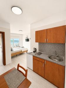 a kitchen with a sink and a room with a bed at Apartmani Villa Amfora - Free Parking in Neum