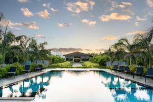 a pool at a resort with chairs and palm trees at The Shore Trishvam in Pondicherry