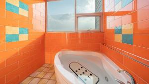 an orange tiled bathroom with a tub with a window at Geoje Wave Hotel & Pension in Geoje