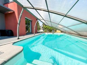 an indoor swimming pool with a glass roof at Élégante maison familiale, terrasse & piscine in Aigrefeuille-sur-Maine