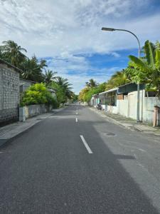 eine leere Straße mit Palmen und einer Straßenlaterne in der Unterkunft Beevaa Inn in Fuvahmulah