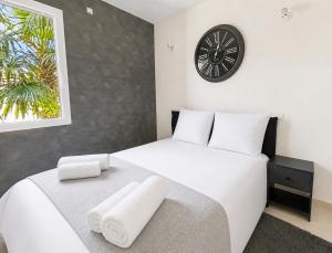 a bedroom with a large white bed with a clock on the wall at Élégante maison familiale, terrasse & piscine in Aigrefeuille-sur-Maine +32 photos