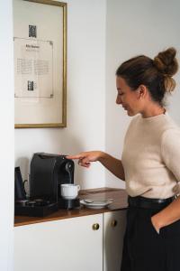 a woman is standing in front of a coffee maker at Theaterhotel & Suites Wien in Vienna