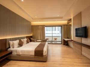 a hotel room with a bed and a flat screen tv at The Lynora in Mysore