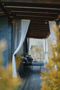 a porch with curtains and a table with flowers at Riverside weekend cabin in Upesciems +7 photos