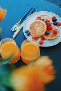 a plate with pancakes and berries and a cup of coffee at Riverside weekend cabin in Upesciems