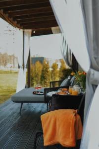 a table and chairs on a porch with a meal on it at Riverside weekend cabin in Upesciems