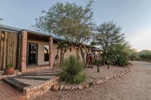 a brick house with trees and plants in front of it at Windhoek Game Camp in Lafrenz Township