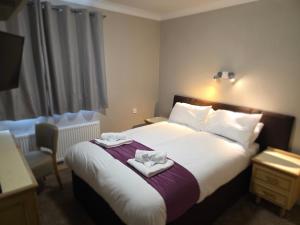 a hotel room with a bed with towels on it at The Paddington House in Warrington +1 photo