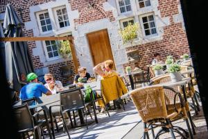 Eine Gruppe von Menschen sitzt an Tischen vor einem Restaurant in der Unterkunft Blanckthys Hotel Voeren in Voeren
