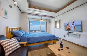 a bedroom with a bed and a couch and a tv at Pension Ora in Samcheok