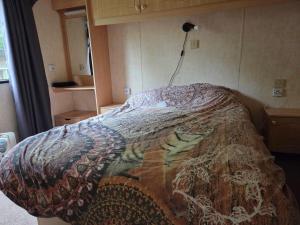 a bedroom with a bed with a blanket on it at Stacaravan Diepenheim in Diepenheim