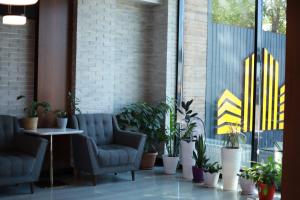 a lobby with two chairs and potted plants at Hotel Mansuri in Almaty