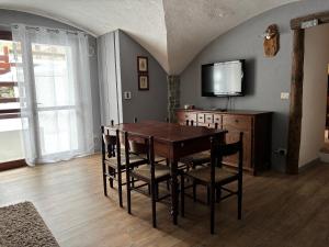 a dining room with a table and chairs and a tv at Appartamento Grangia Rigat, Bousson, Cesana Torinese in Bousson