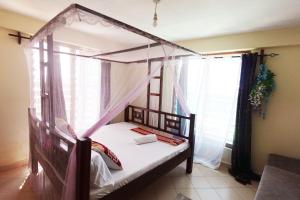 a bedroom with a canopy bed and a window at The Nest Apartment Darad in Ukunda Airport