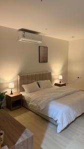 a bedroom with a large bed with two lamps on it at Apartment in Al Kharj
