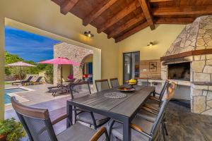 a dining room with a table and chairs and a fireplace at Holiday house MARLY with private pool in Kras